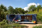 Owner Stacey Hill was instantly drawn to this shipping container’s existing blue color and chose to leave it unchanged. Architect Jim Poteet added floor-to-ceiling sliding doors to allow light in, as well as a cantilevered overhang to shade a window on the left side, which houses a small garden storage area.