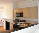 Chris removed the existing cabinets, microwave, oven, and stove from the cutout in the kitchen and filled it in with Ikea cabinets to create a flush wall that runs nearly the entire length of the public space.