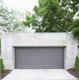 The darker gray garage door offers a chromatic and textural contrast to the concrete shell.