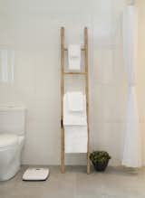 A simple bamboo ladder holds towels in the master bathroom, whose floors are radiant-heated. Just beyond the curtain at right is the curbless shower. Toto toilet.