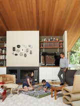 Living Room, Chair, End Tables, Light Hardwood Floor, Standard Layout Fireplace, Sofa, and Stools As his parents look on, Apolo plans his commute under a fire-top piece by the artist Michael Ricardo Andreev and alongside a Wiggle chair by Frank Gehry.  Photos from Undivided Intentions