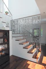 In a renovation of an existing farmhouse, a hanging screen composed of aluminum circles and lines, cut with a CNC water jet, separates the entry from the staircase and rear kitchen area.