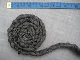 4. On a work surface, lay the braid flat. Take one end of the braid and coil the braid around itself in a circular motion to create the base of your container. Create a 3" base. Pin each row of the coil into place.  Search “cascade coil drapery” from Braided Rag Vessels