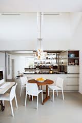 The kitchen frames a natural division between the public and private spaces of the house. The couple's private dining area features a round wooden table by Frank Bolink, and white chairs that are from Hema, a low-cost Dutch retailer.  Photo 4 of 14 in This Home Takes Recycling to the Next Level