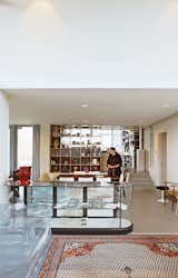 A view from the main entrance, looking toward the kitchen, reveals part of the public space of the house. Blans bought the vintage glass display case from a retailer. Behind it, the early 20th-century Amsterdam school dining table, formerly her grandmother's, has been carefully restored. The stairs lead to the builder's lift, kitchen, and the couple's private living and work area.
