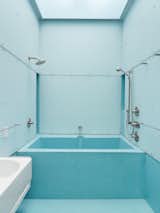 Designer Andrew Dunbar describes the bathroom as an outside-in room because it has light, air, and sometimes, when it drizzles and the skylight left open, even rain. Designed for exactly these circumstances, a blue-glass mosaic tile floor is laid at an angle to drain with ease.