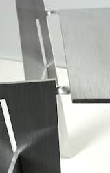 Each chair is folded from a sheet of 6-mm-thick aluminum. The points where the metal is twisted become delicate-looking hinges.