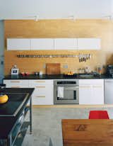 Concrete floors and an Ikea kitchen and spice rack make for an affordable, cleanly geometric aesthetic at the back of the bottom floor. The appliances are by Frigidaire, and the black countertops are sealed with Eco Tuff by Eco Procote.
