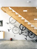 More adult playthings, like this pair of bikes live under the stairs, whose cutouts break up the plane of plywood and double as peepholes for kids at play.