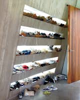 Just off an internal courtyard, a mudroom provides a prime place to keep sneakers. Each family member has their own shelf, backlit by windows that illuminate every pair.