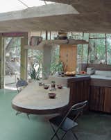 At a smaller scale than an entire building, a concrete, cantilevered countertop and table extends both inside and outside at the Arizona home of Italian architect Paolo Soleri. A sculptural shelf frames the window and door beyond, with rounded edges for a soft, supple feel.