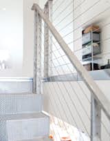 A mixture of perforated, bent-steel plates, tension cables, and galvanized-steel handrails and posts form a modern staircase that feels light and airy, despite its industrial materials. The perforations in the steel steps and the thinness of the tension cables keep the stair feeling open and transparent. Designed by architect John DeSalvo, it was inspired by a high-end staircase by French architect Jean Nouvel.