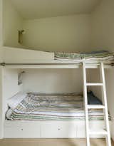 In the boys' room, a rolling ladder provides access to the top bunk.