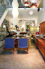 A long view of the appealingly cluttered shop, with a Noguchi paper lamp and a pair of wool-upholstered teak chairs in the foreground.