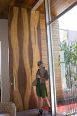 The front door is an awe-inspiring, 14-foot, mixed wood creation made by L.A. custom door fabricators Real Door Inc. The wood used in making the door were mostly leftovers from the shop, says Dino of Real Door Inc. A gentle wave pattern accentuates the material's natural grain.