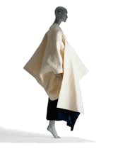 This coat from Rei Kawakubo's 1983-1984 Autumn/Winter collection for Comme des Garcons is made of wool felt. Though it has a strong, sculptural form when worn, it's actually made of two panels, the smaller of which slides through a slit in the larger piece and hangs from the side of the chest. There are no buttons or fasteners.