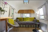 Here's the finished sofa bed. The sofa is upholstered in Designers Guild fabric. The curtains are from Ikea. The chair is from Cost Plus. And the wall cupboard above incorporates some of the trailer's original mahogany wood.  Photo 2 of 8 in 8 Ways to Renovate an Airstream by Erika Heet from Big Sur Airstream Renovation