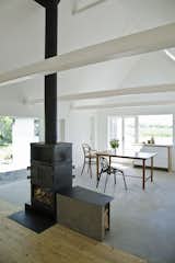 This summer house, renovated by Jonas Labbé and Johannes Schotanus of LASC for a family in Skåne, Sweden, features&nbsp;a two-sided stove, elevated slightly to bring the fire closer to eye-level. The stove marks the meeting of the new concrete floor with the old wooden floor.