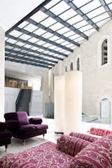As conceived by Safdie, a pristine ceiling of glass and steel tilts to meet Mamilla Hotel’s grand structure of Jerusalem stone. Sunlight pours through, bathing the interiors with warmth and brightness. Eggplant-hued lounges cozy up the sitting area as well.