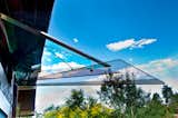 The awning itself, affixed to the facade of the mid-1960s house, is comprised of four pieces of fused, 3/8" thick, tempered glass. The zinc washers, stainless steel tubes, and other hardware were picked up at a local hardware store. The only elements Michl went higher end on were the metal bars and airline cable. Winds of up to 60 mph can hit the house so structural integrity was paramount.