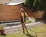 Helen Rice watering the garden outside of her Charleston residence.  Search “locations--back-yard” from Raise High the Roof Beams