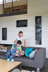 The open-plan living room and kitchen are a giant playground for five-year-old Suresh and his parents, as is the durable sofa and table base from Room & Board. Steel alcoves inset into the white-stained cedar wall shelter firewood, books, and treasured objects.  Photo 6 of 10 in An Epic Plot