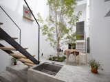It’s not easy to transform a 15-foot-wide building site—wedged between houses in every direction—into a home that feels more spacious than its location allows. Mamm-design’s solution was to dedicate two-thirds of this tiny 653-square-foot house in Tokyo to a 20-foot-high garden room to bring a sense of the outdoors in. A centrally positioned evergreen ash anchors the airy terrace, which is paved with complementary gray bricks. The kitchen, bedroom, bathroom, and workspace are all connected to the central space, transforming the covered veranda into a surrealistic theatrical setting for day-to-day life.