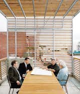 A patio protected by a steel-and-cedar-slat trellis accommodates a meeting between (left to right) contractor Mark Farha, building owners and developers Brock Oaks and David Farha, and owner and contractor Ted Farha.