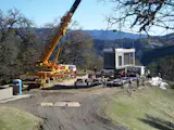 After workers tore off the shrink wrap, the crane lifted the first module off the semi truck.