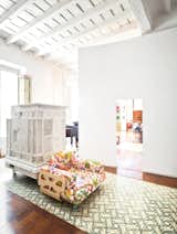 Paths of Andalusian tile and intervening plaster walls help to delineate space in the expansive apartment, which is centered around an internal entry courtyard. The armchair, designed by Peter and Alison Smithson, is covered in a Josef Frank textile from Just Scandinavian. The white piece just behind it is a repurposed Austrian stove that’s now used as a storage device.