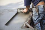 Using a hand trowel to tidy the edge where a door tread will rest flush with the concrete floor.
