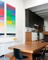 The architect designed the kitchen cabinetry, and used wood left over from the demo of the house’s exterior wall for the dining table. A piece by Nicolas Grenier hangs above a cabinet the residents found at a garage sale.