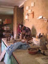 There are a pair of potter's wheels in the back of the studio. Here one of Thiel's workers throws some small vases.