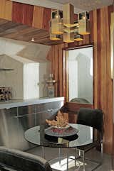 Dining Room, Table, Chair, and Pendant Lighting The eat-in kitchen features poured-in-place concrete countertops and redwood wall paneling.  Search “monadnock building architectural sculpture” from John Lautner's Desert Rose