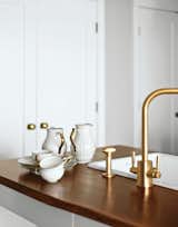 A Rohl faucet was stripped and replated in brushed brass. The modern fixtures prove a lovely contrast to the American walnut countertops and original Rosenthal dishware.