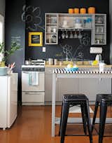 This kitchen manages to look playful and edgy with chalkboard paint: the matte black is crisp, but the scribbles add whimsy. Reprinted from The First Apartment Book by Kyle Schuneman. Copyright © 2012.  Published by Clarkson Potter, a division of Random House, Inc.  Photo 3 of 3 in The First Apartment Book: Cool Designs for Small Spaces