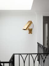 The gold (nonfunctioning) surveillance camera by artist Camp Bosworth in the stairwell previously hung in the glass entryway of the family’s former house in Houston.