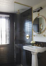 The bathrooms are clad in black Daltile and features brass hardware from Watermark in the European-style shower and on the sink. The mirror is custom. ASH worked with American Medicinal Arts on the custom-scented toiletries. "Because we are designers as well as developers, we pay very close attention to physical detail," Heckman says. "For us, part of the fun of doing a hotel was being able to focus on all of the touch points in a way you are not often able to on residential projects. It is tough to describe, but one of the main 'amenities' of The Dean is staying in a property where every detail, no matter how minute, has been thought about."  Photo 14 of 15 in The Dean Hotel in Providence by Diana Budds