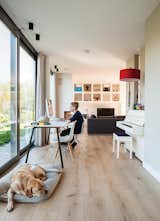 Bram sits at a table by Gispen in the oak-floored public side of the house, facing the water, while the dog, Bommel, relaxes nearby. "We really like the indoor-outdoor effect," says Bram's dad, Mark de Graaf. "The ground floor opens on three sides—on a summer day, it stays cool."