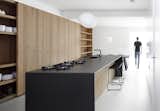 The kitchen island is made of oak with a thin, black stone countertop.