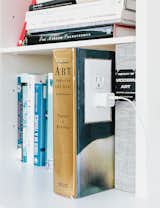 Living Room The garage is an exercise in “hide and reveal.” The Corian shelf features an outlet in a converted book, a detail that brings delight to a mundane task. “We wanted to make the experience of plugging in a phone or computer joyful,” Grizzle says.  Photo 3 of 7 in Bookshelves We Love by Aileen Kwun from This Renovated Garage is the Ultimate Modern Party Space