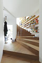 Bookshelves add extra utility to the undulating staircase in Tokyo's 921-square-foot Coil house. The space was designed by architect Akihisa Hirata for Sakura and Ryo Sugiura, a young couple with two children.