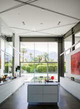 Kitchen, Ceiling, Concrete, and Recessed In the kitchen, which faces west to capture views of the San Jacinto Mountains, a large red work by James Jensen punctuates one wall. The induction cooktop is from Gaggenau; the sinks were sourced from Blanco.  Kitchen Recessed Photos from An Energy-Efficient Hybrid Prefab Keeps Cool in the Palm Springs Desert