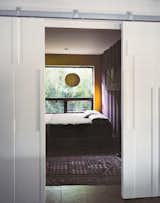 Though many of the interior surfaces have been spray-foam insulated and covered in Sheetrock, the couple, drawn to the natural patina of the shipping containers, opted to keep select areas of the material exposed. Closed off by bas-relief doors designed by Mathesius, the main guest room is one of few spaces that put whole walls of the raw surface on display, painted in Benjamin Moore’s warm Kalamata and Wasabi hues. benjaminmoore.com