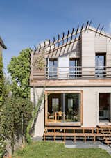 The back of the house was designed by owner-architect Caroline Djuric as a contemporary counterpoint to the more traditional front facade. A pergola reaches beyond the roof and over the deck on the second story. An asymmetrical wooden stairway leads down to the garden.