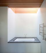 A large skylight looms above a Duravit tub and a Runtal Radia towel warmer in the en suite bathroom.