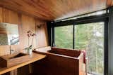 The Japanese-style bathroom, which is clad in teak, features a matching tub and sink by Bath in Wood.
