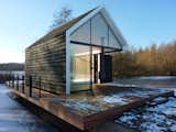 Utilized year-round, the 225-square-foot cabin opens up to the surrounding countryside via parallel glass walls on either end and a folding wood door that leads to the terrace. Co-designer Remko Remijnse of 2by4 Architects says the concept was to make the “natural surroundings become part of the living room [so] you have endless living space.”  Photo 2 of 5 in WEST BOLTON by Louis-martin Duval from Glass Prefab Cabin is Ultimate Outdoor Getaway