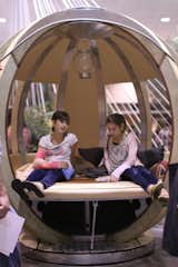 Two show goers recline in a G Pod by Mars Labs.