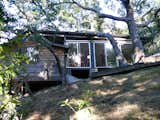 On the opposite side of the house stands an old oak grove; the views to it are enhanced by floor-to-ceiling sliding doors, which, when opened, create a natural breezeway through the house. Jantzen was able to sneak the roofline in just under an existing branch. At left is the small bedroom of the original cabin.